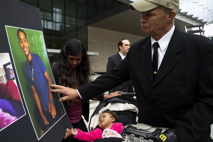 John Weber, the father of 16-year-old shooting victim Anthony Weber, reaches out to touch his son's photo during a news conference outside the federal courthouse in downtown Los Angeles on Wednesday. Anthony was killed by Los Angeles County sheriff’s deputies in February.