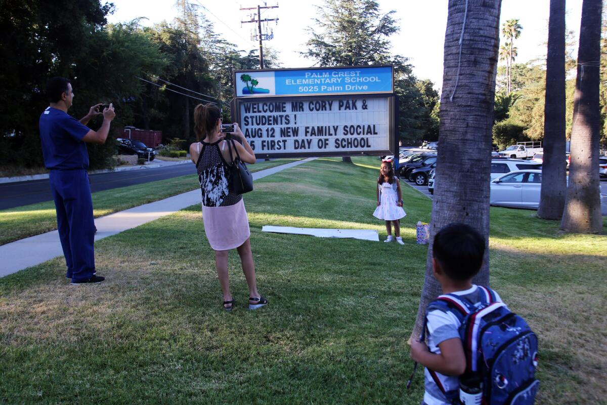 Parents from Palm Crest Elementary School take pictures of their kids in front of the school's marquee on the first day of the school year at Palm Crest Elementary School in La Cañada on Thursday.