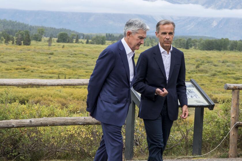 Jerome Powell, Chairman of the Board of Governors of the Federal Reserve System, left, and Bank of England Governor Mark Carney, right, walk together after Powell's speech at the Jackson Hole Economic Policy Symposium on Friday, Aug. 23, 2019, in Jackson Hole, Wyo. (AP Photo/Amber Baesler)