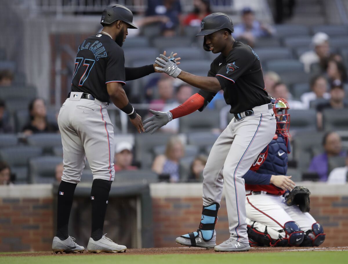 Miami Marlins' Jesus Sanchez, right, celebrates with Bryan De La Cruz (77) after hitting a two-run home run off Atlanta Braves pitcher Ian Anderson during the first inning of a baseball game Friday, Sept. 10, 2021, in Atlanta. (AP Photo/Ben Margot)