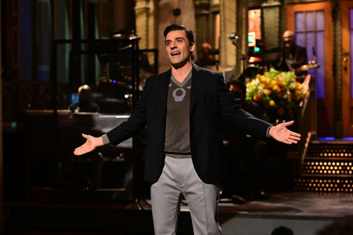 Oscar Isaac talking with his arms outstretched on a stage