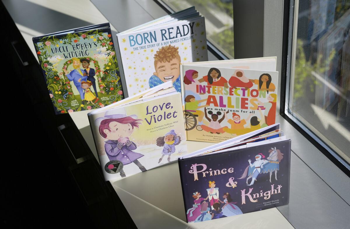 Five LGBTQ+ children's books are displayed on the window sill.