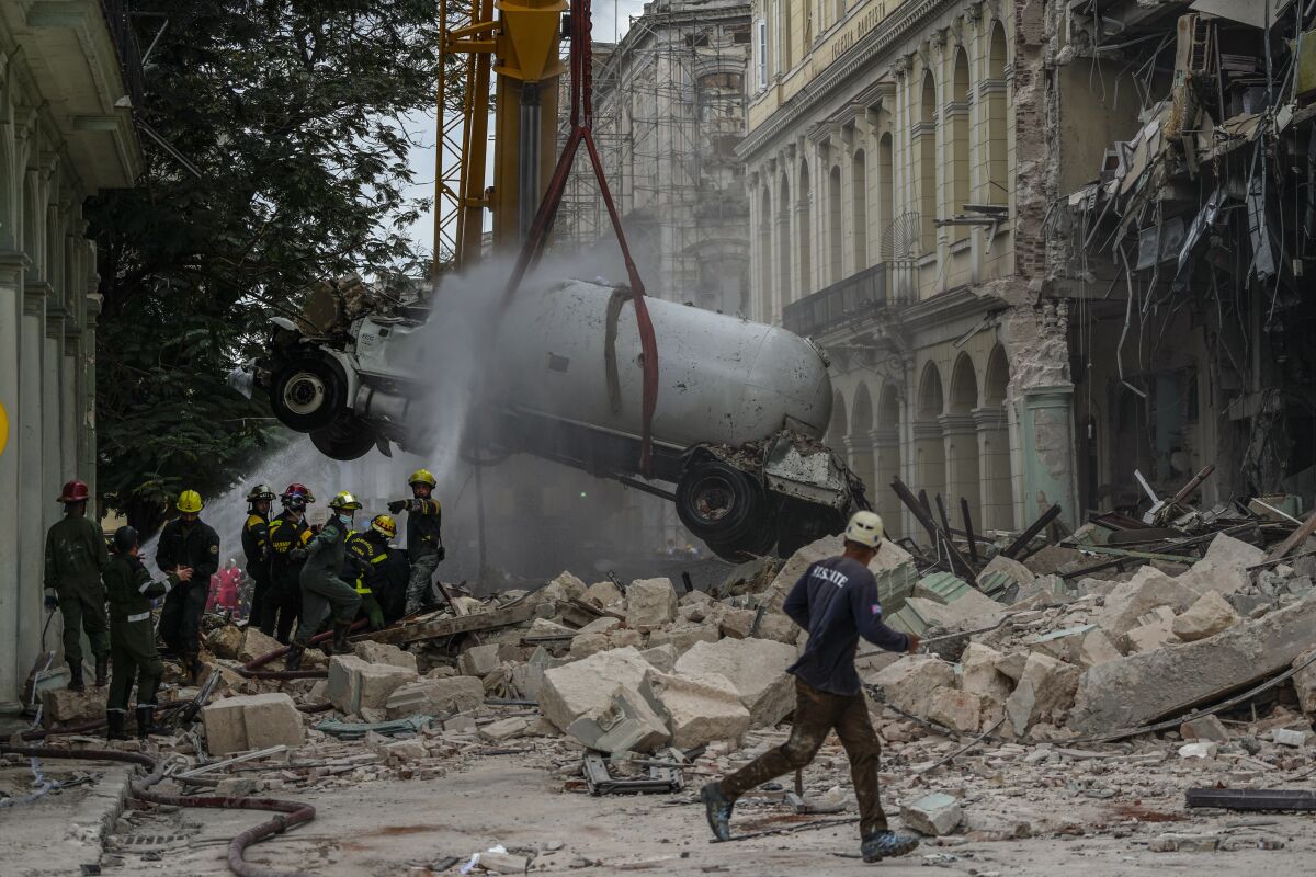 Firefighters spray a tanker truck with water in order to cool it down as they remove it from the site of a deadly explosion that destroyed the five-star Hotel Saratoga, in Havana, Cuba, Friday, May 6, 2022. A powerful explosion apparently caused by a natural gas leak killed at least 18 people, including a pregnant woman and a child, and injured dozens Friday when it blew away outer walls from the luxury hotel in the heart of Cuba’s capital. (AP Photo/Ramon Espinosa)n Espinosa)