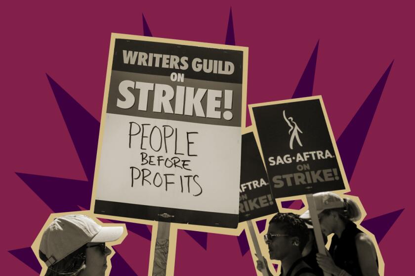 Writers Guild and SAG-AFTRA members hold picket signs.