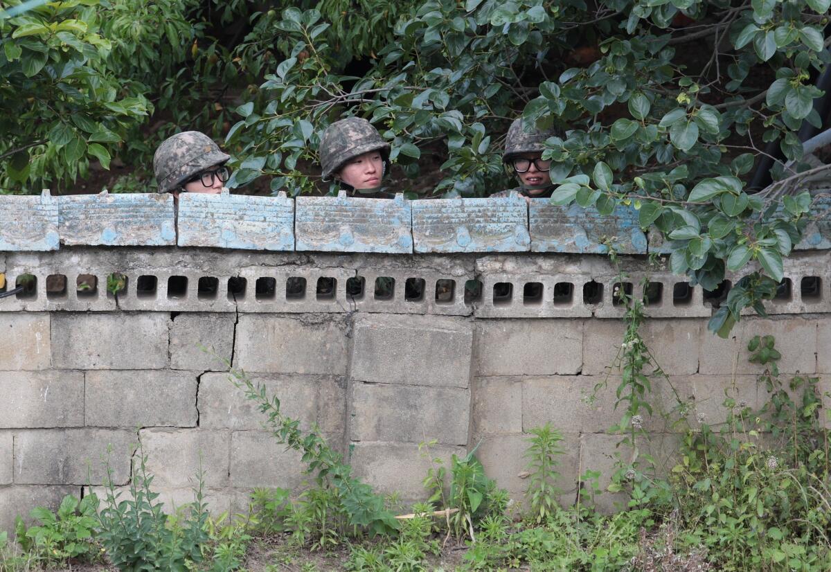 South Korean soldiers hide behind a wall of a private house during a gunfight with a runaway comrade.