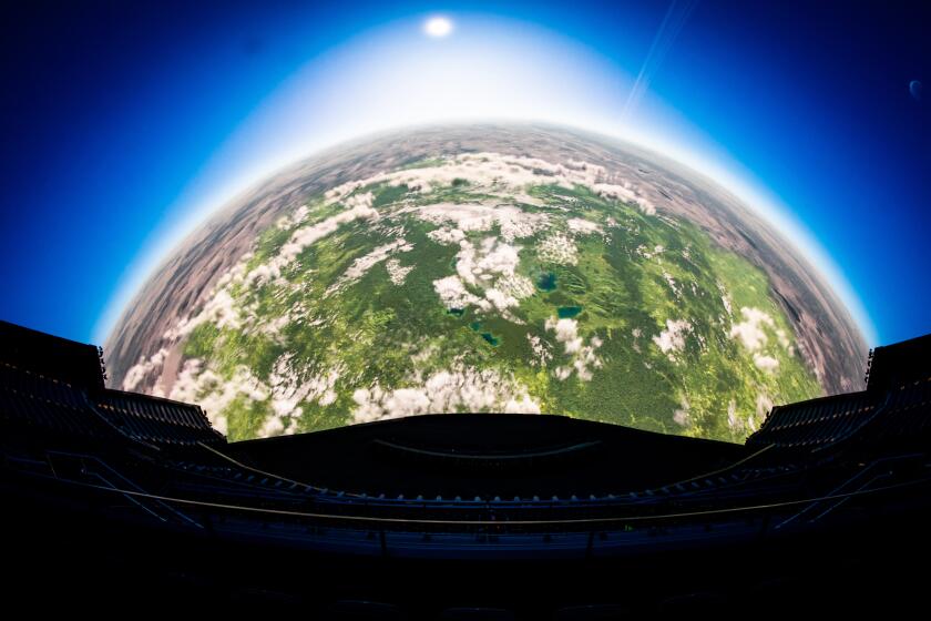 A view of the earth from space is seen ona massive screen inside an empty theater. 