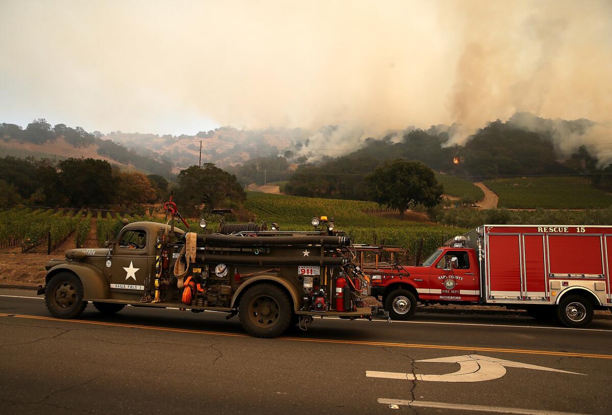 A resident moves a vintage fire truck out of an evacuated area as an out of control wildfire moves through Yountville, Calif.