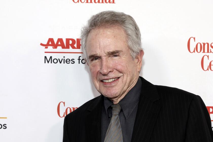 An old man with white hair smiles in a dark suit