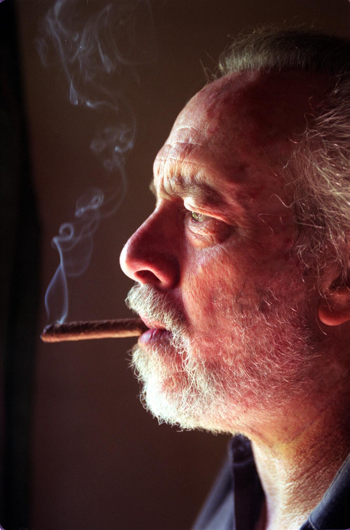 A profile shot of Robert Towne smoking a cigar.