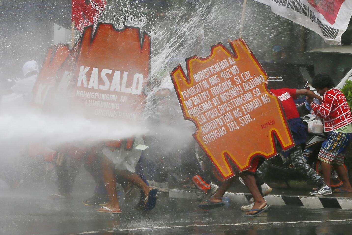 A firefighter aims his hose at surging protesters as they force their way toward the U.S. Embassy in Manila, Philippines, on Oct. 19, 2016.