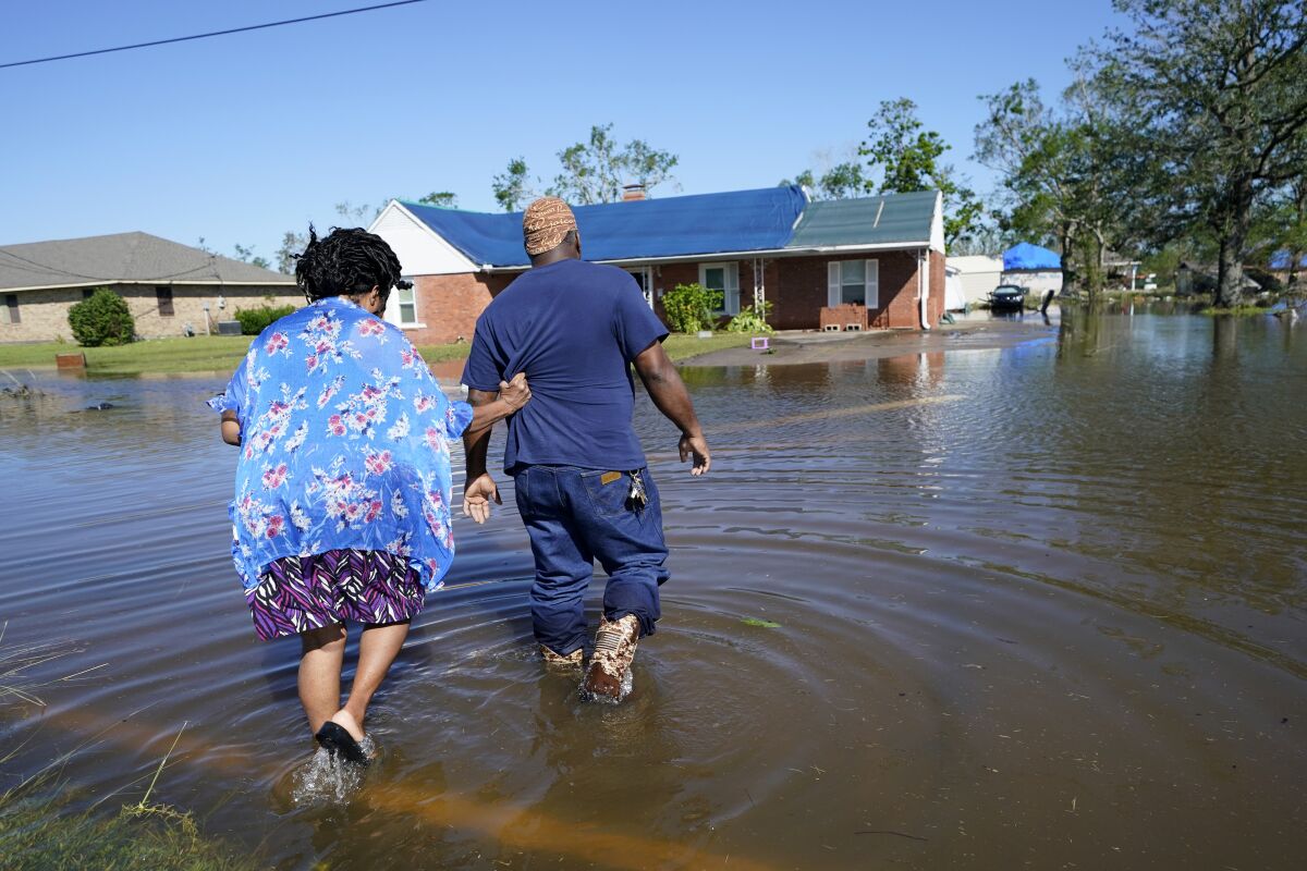 Soncia King holds onto her husband Patrick King in Lake Charles, La., Saturday, Oct. 10, 2020, as they walk through the flooded street to their home, after Hurricane Delta moved through on Friday. (AP Photo/Gerald Herbert)