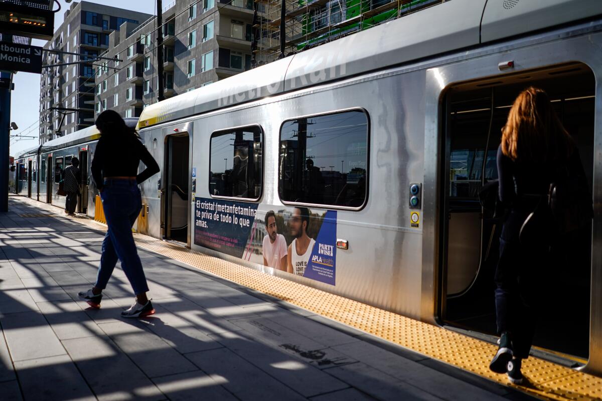 People disembark and board an E Line train in Santa Monica in 2019.