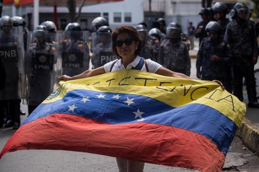 Una mujer ondea una bandera venezolana durante una marcha estudiantil en Caracas (Venezuela). EFE/Archivo