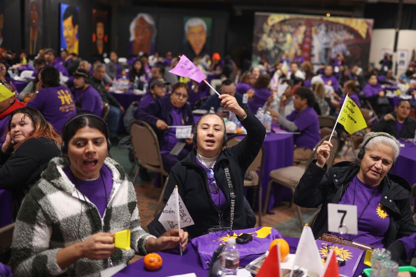 Watts, CA - February 9: (From left) Fernando Rosales, Lourdes Farfan, and Zulma Riveria hold flags supporting the union during a California Fast Food Workers Union meeting at Watts Labor Community Action Committee on Friday, Feb. 9, 2023 in Watts, CA. (Michael Blackshire / Los Angeles Times)