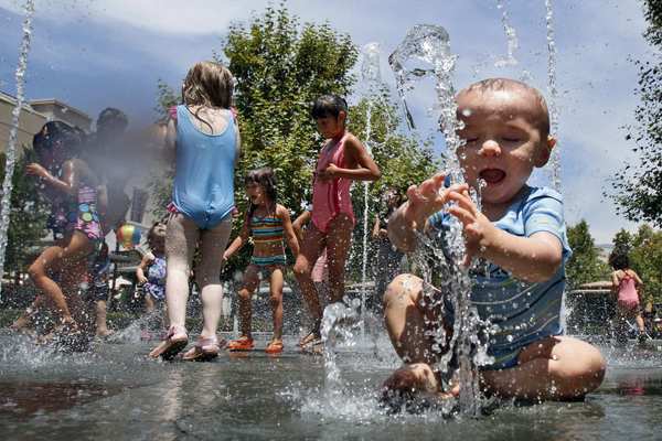 Nine-month-old Trevor Brady, right, plays among bubble jet fountains at Victoria Gardens in Rancho Cucamonga.