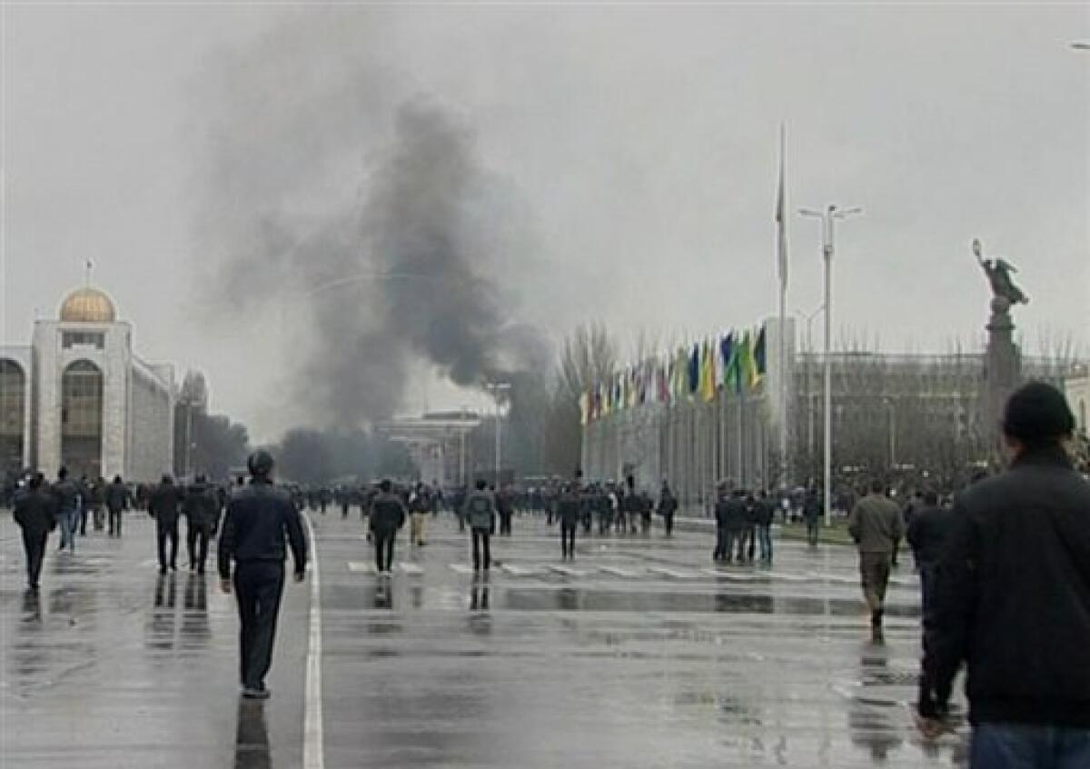 In this image taken from television, crowds gather on central square as smoke rises in Bishkek, Kyrgyzstan, on Wednesday, April 7, 2010. Anti-government protests have swept across the Central Asian nation of Kyrgyzstan and riot police have opened fire on thousands storming the main government building in the capital of Bishkek. (AP Photo/APTN) TV OUT