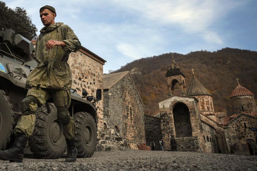 A Russian peacekeeper walks past his Armoured Personnel carrier (APC) stationed in front of the 12th-13th century Orthodox Dadivank Monastery, outside the town of Kalbajar on November 15, 2020, after the monastery was put under their protection during the military conflict between Armenia and Azerbaijan over the breakaway region of Nagorno-Karabakh. - Kalbajar is one of the seven districts which will be transferred to Azerbaijan as part of a deal on Nagorno-Karabakh. (Photo by Alexander NEMENOV / AFP) (Photo by ALEXANDER NEMENOV/AFP via Getty Images)