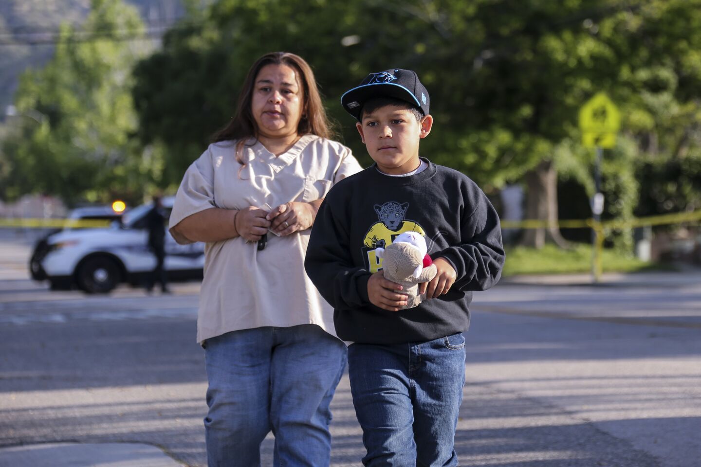 Denna Lopez and her 9-year-old son, Raymond Lopez, brings a stuffed animal to place at a makeshift memorial for the shooting victims at North Park Elementary School in San Bernardino.