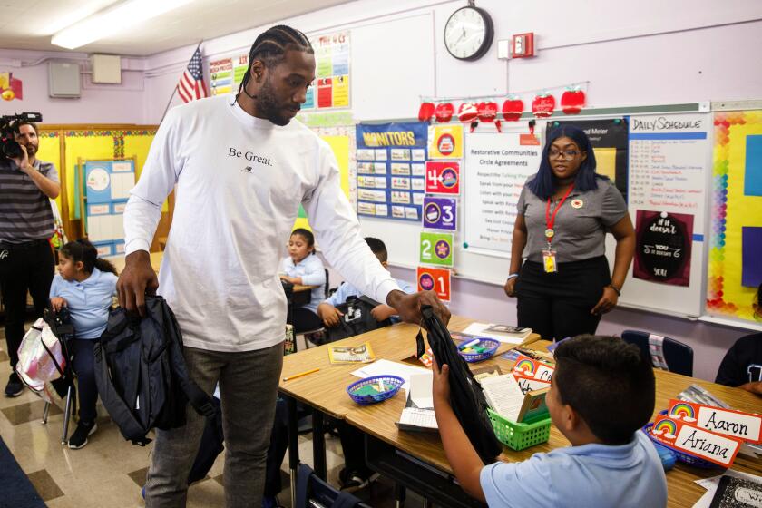 Patrick T. Fallon  For The Times KAWHI LEONARD, giving a student at 107th Street Elementary School in Watts a backpack, donated 1 million backpacks to three Southland school districts.
