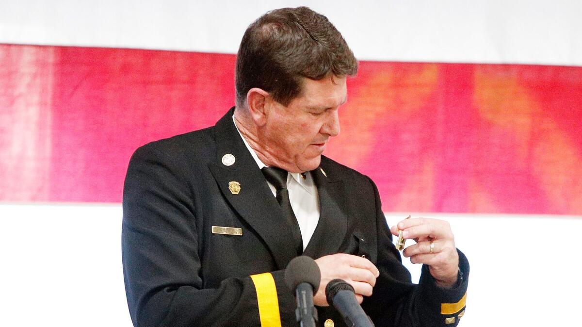 Outgoing Burbank Fire Chief Tom Lenahan removes his chief's badge during the change-of-command ceremony at the department's headquarters