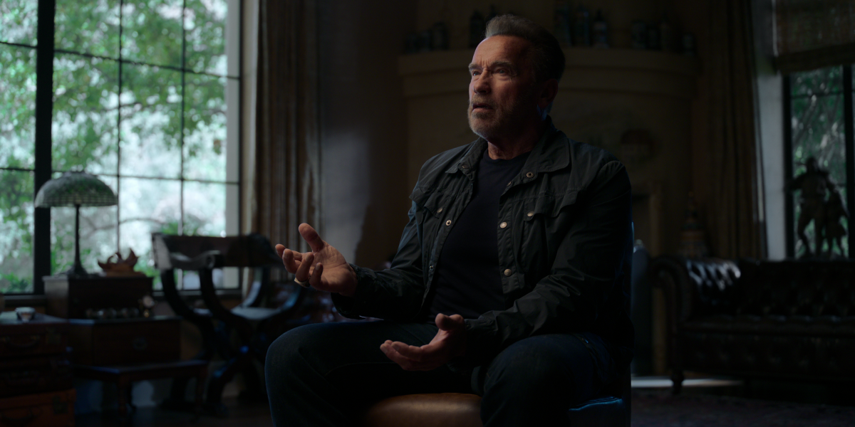 Arnold Schwarzenegger, sitting for an interview, motions with his hands
