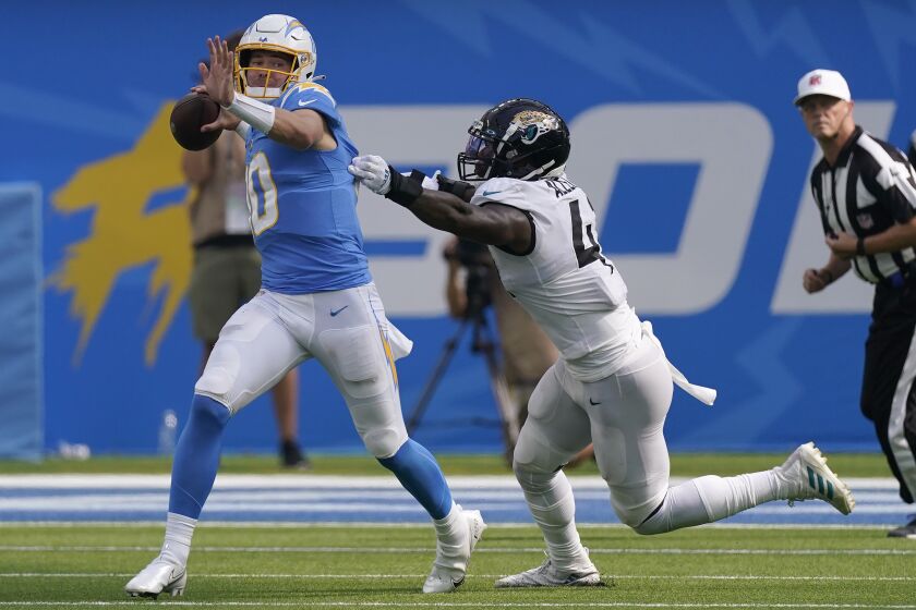 Los Angeles Chargers quarterback Justin Herbert, left, passes while pressured by Jacksonville Jaguars linebacker Josh Allen during the second half of an NFL football game in Inglewood, Calif., Sunday, Sept. 25, 2022. (AP Photo/Mark J. Terrill)