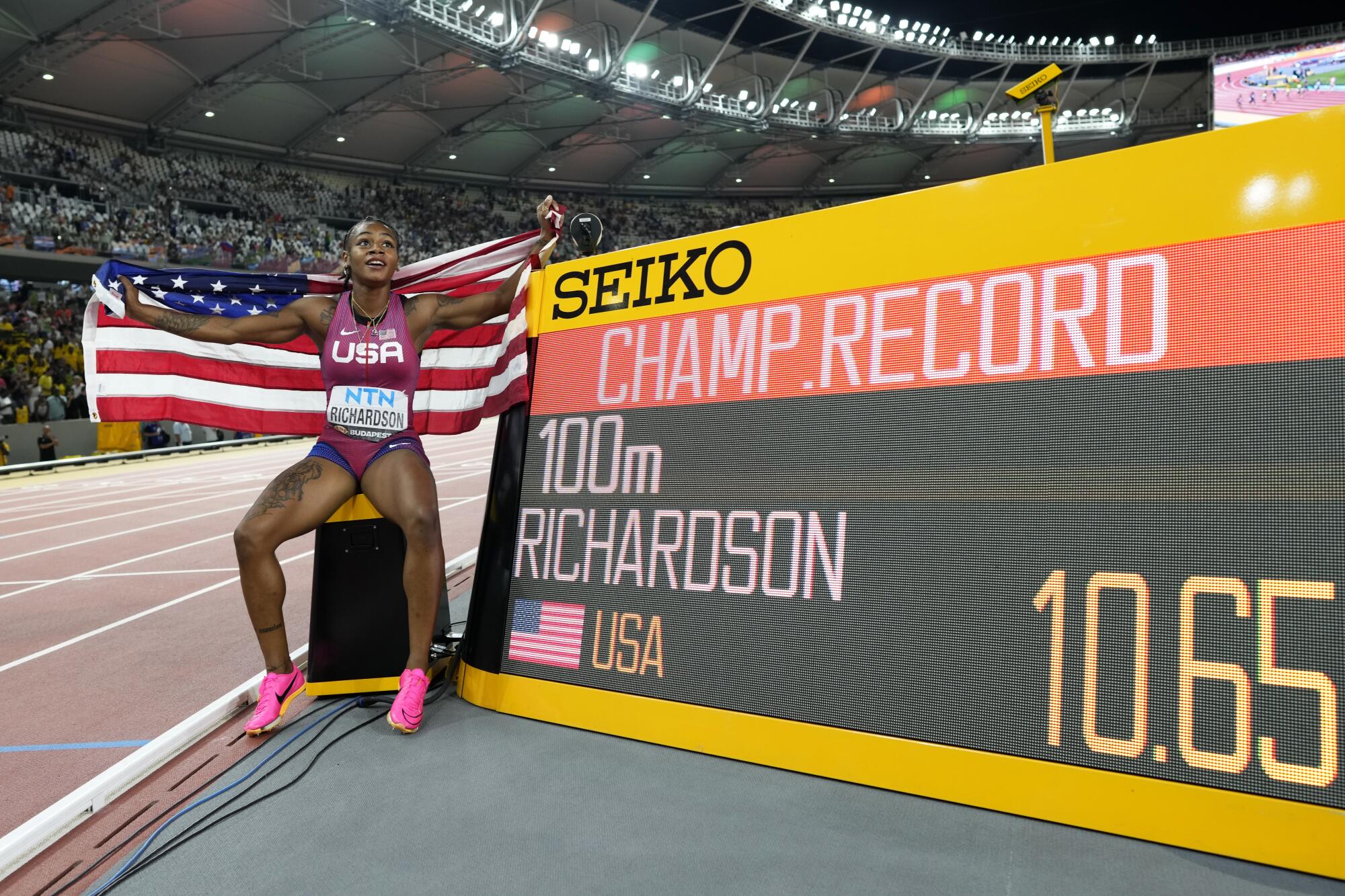 Sha'Carri Richardson poses next to a videoboard displaying her winning time for 100 meters at the world track championships.