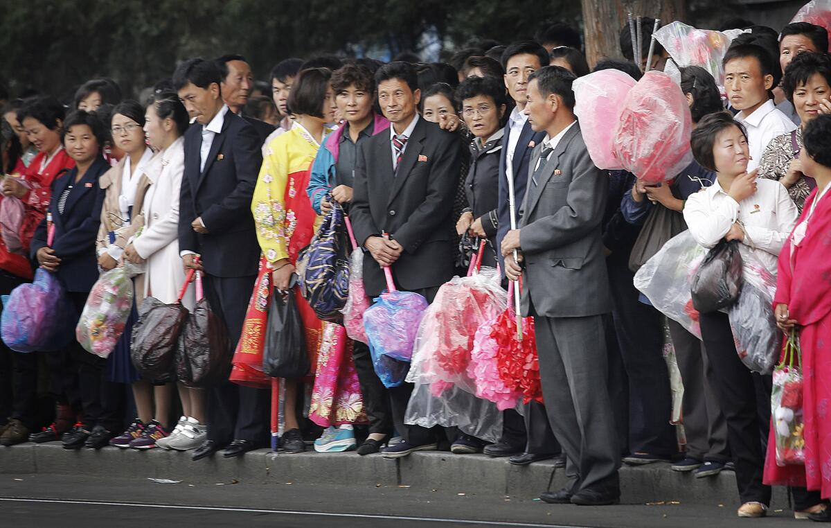 North Koreans waiting at a trolley stop in Pyongyang on Oct. 8 carry flowers to be used at the ruling party's anniversary celebrations.