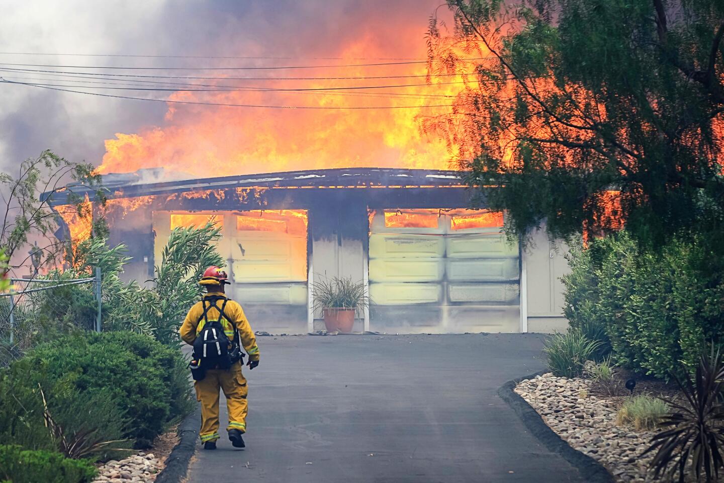 A firefighter approaches a burning home along Olive View Road on Friday during a fire in Alpine, California.