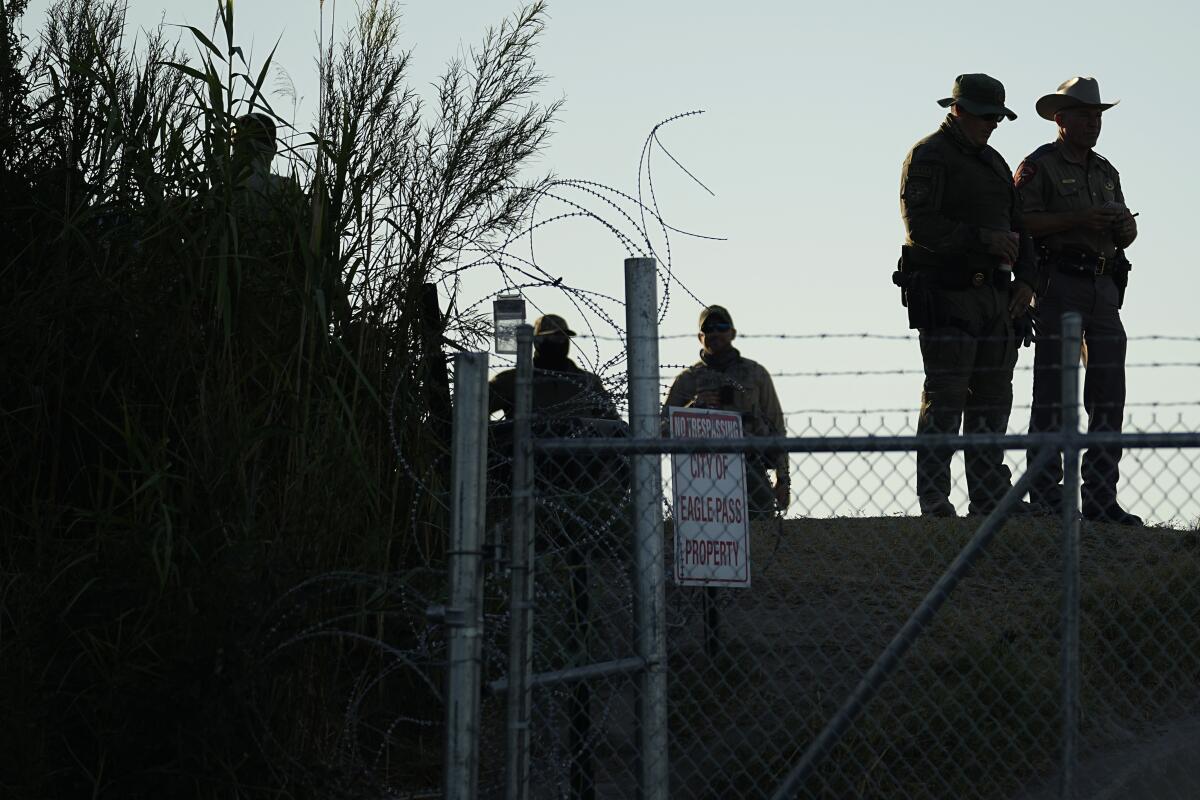 Policías estatales de Texas vigilan junto a un letrero de "Prohibido el paso" y alambre de púas