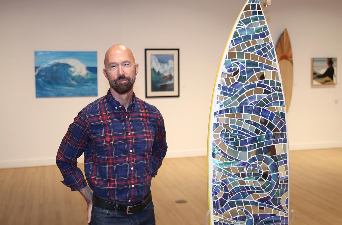 Dan Faltz stands in front of a mosaic surfboard in the main showroom at the "Surf City ART" exhibit.