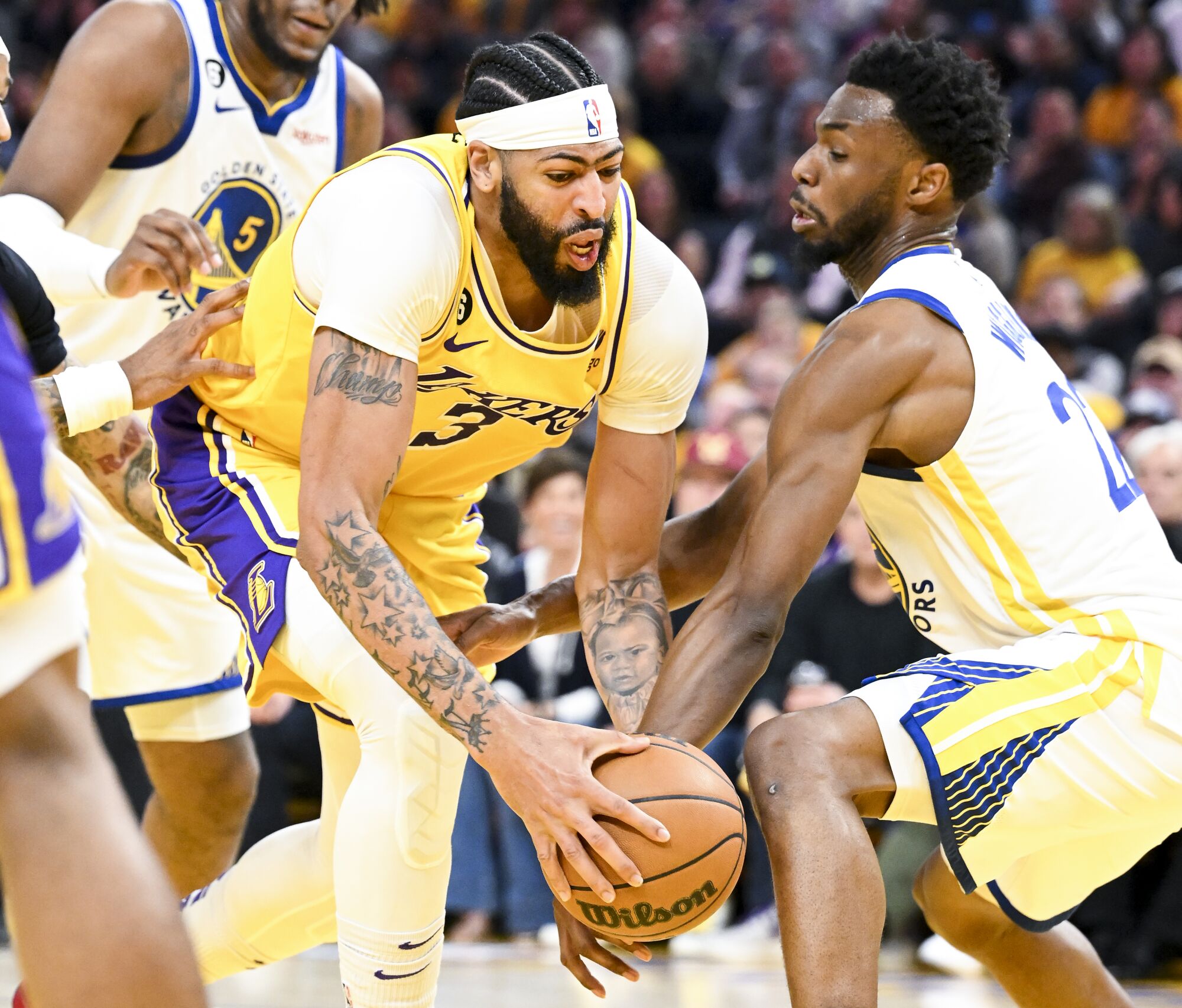 Warriors forward Andrew Wiggins reaches to pocket the ball from Lakers forward Anthony Davis.
