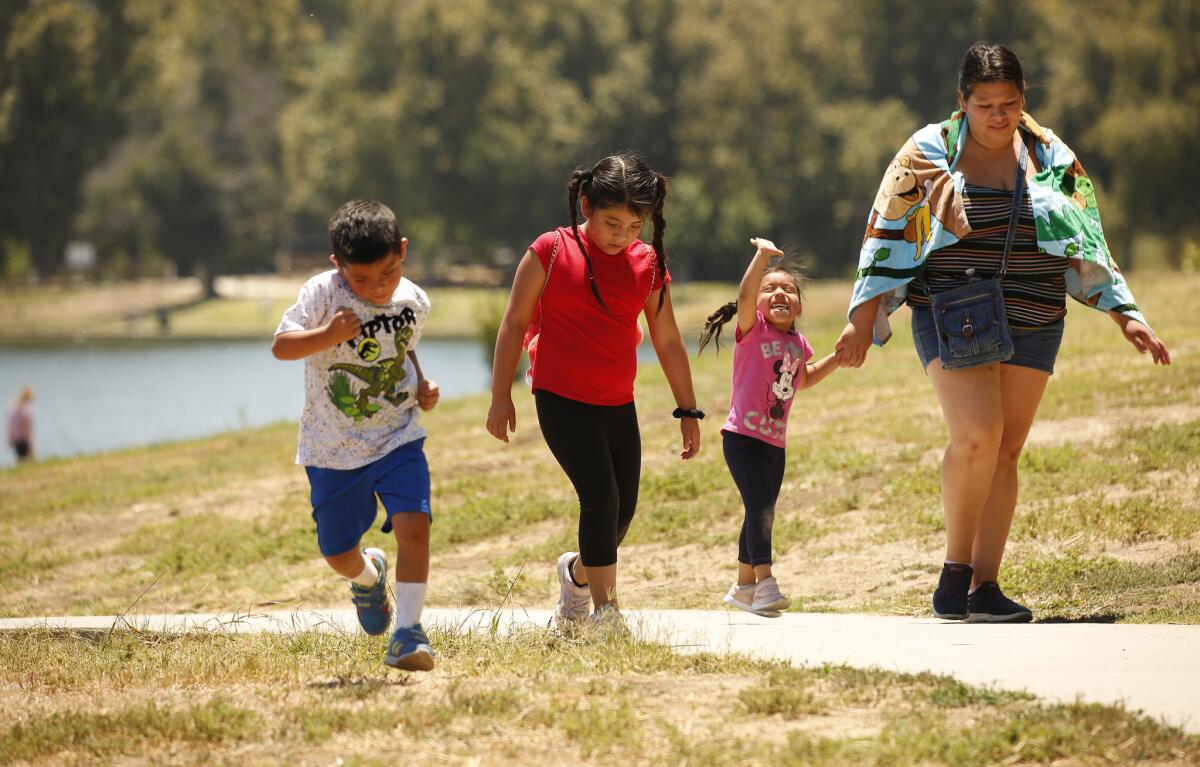 Vanessa Santos walks her children Keily, 7, Kevin, 4, and Cecelia, 3, at Lake Balboa Anthony C. Beilenson Park in Encino.