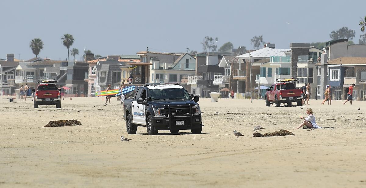 Newport Beach lifeguards and police clear the beach Saturday. Another sweep took place on Sunday.