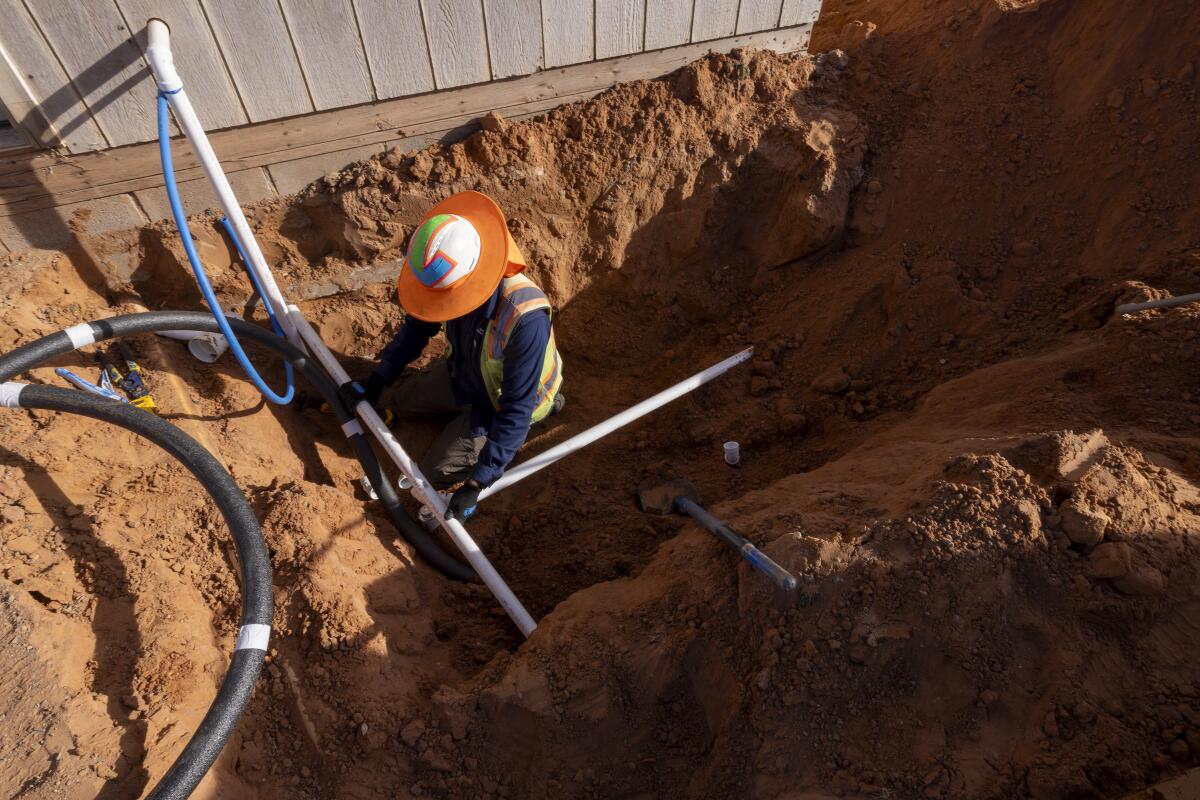 DigDeep 员工 Donovan Smallcanyon 在沟渠中安装新的排水管。
