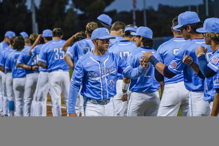 SAN DIEGO, CA - FEBRUARY 18: USD Toreros Head Baseball Coach Brock Ungricht, center, fist bumps his players during the opening ceremonies before his first game as head coach, which was against the Oregon Ducks Friday Feb. 18, 2022. (Howard Lipin / For The San Diego Union-Tribune)
