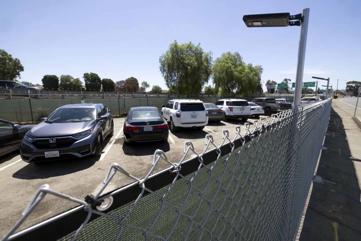 A row of parked cars behind a chain-link fence.