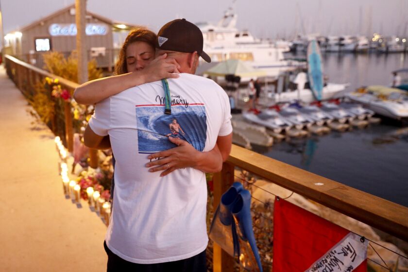After hanging a dive flag in memory of the victims, JJ Lambert, 38, who said he had dived on the Conception as a kid, is hugged by Jenna Marsala, 33, near the Sea Landing offices in Santa Barbara Harbor where the Conception departed from.