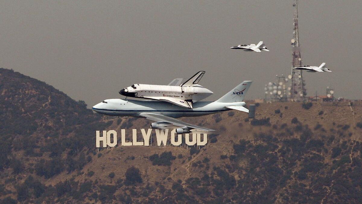 The space shuttle Endeavour passes the Hollywood sign.