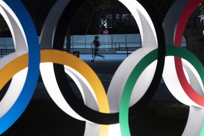 In this March 30, 2020, file photo, a man jogs past the Olympic rings in Tokyo.It’s been six months since the Tokyo Olympics were postponed until next year by the COVID-19 pandemic. Everyone from new Japan Prime Minister Yoshihide Suga to IOC President Thomas Bach have tried to assure the Japanese public and deep-pocketed sponsors that the Olympics will take place. (AP Photo/Jae C. Hong, File)