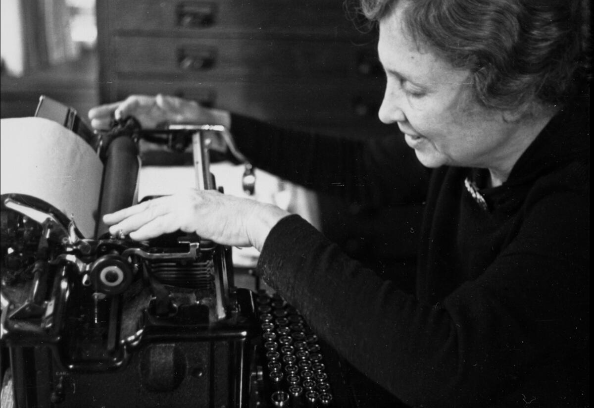 Helen Keller sits at a typewriter.