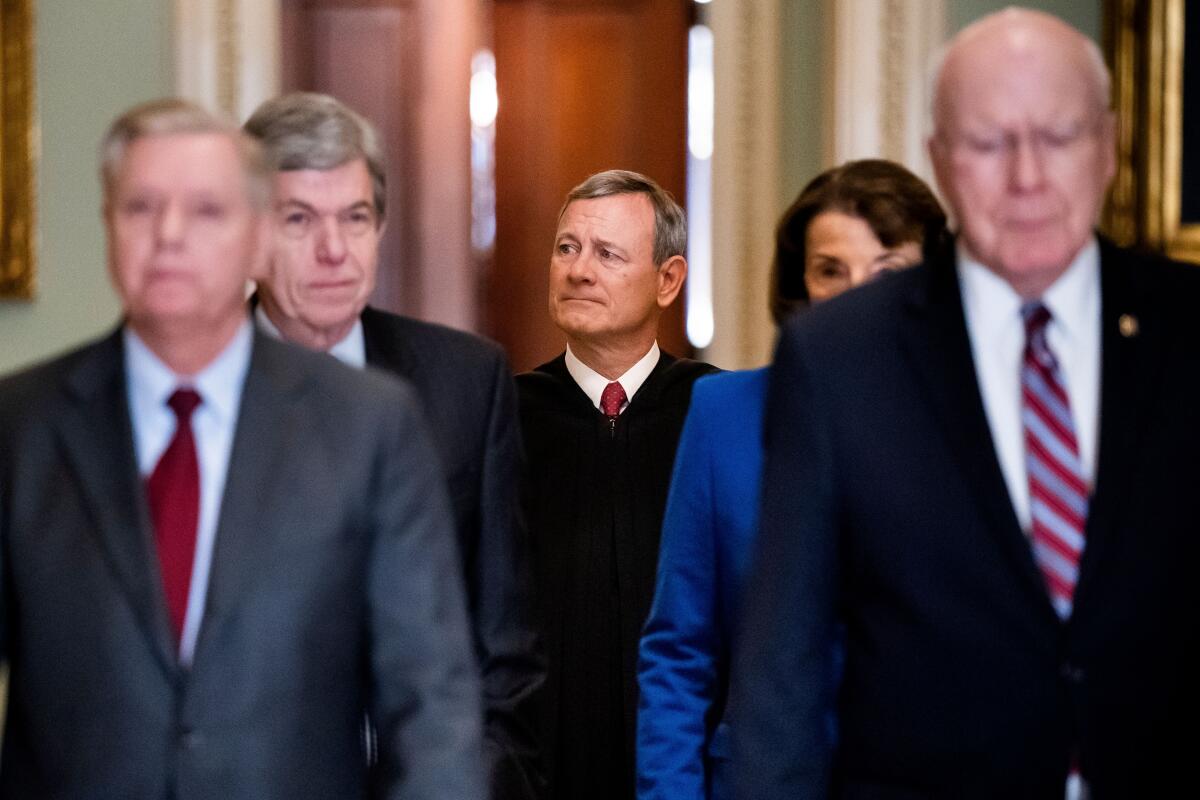 Chief Justice John G. Roberts Jr., center, arrives at the Senate to swear in lawmakers for President Trump's impeachment trial. 