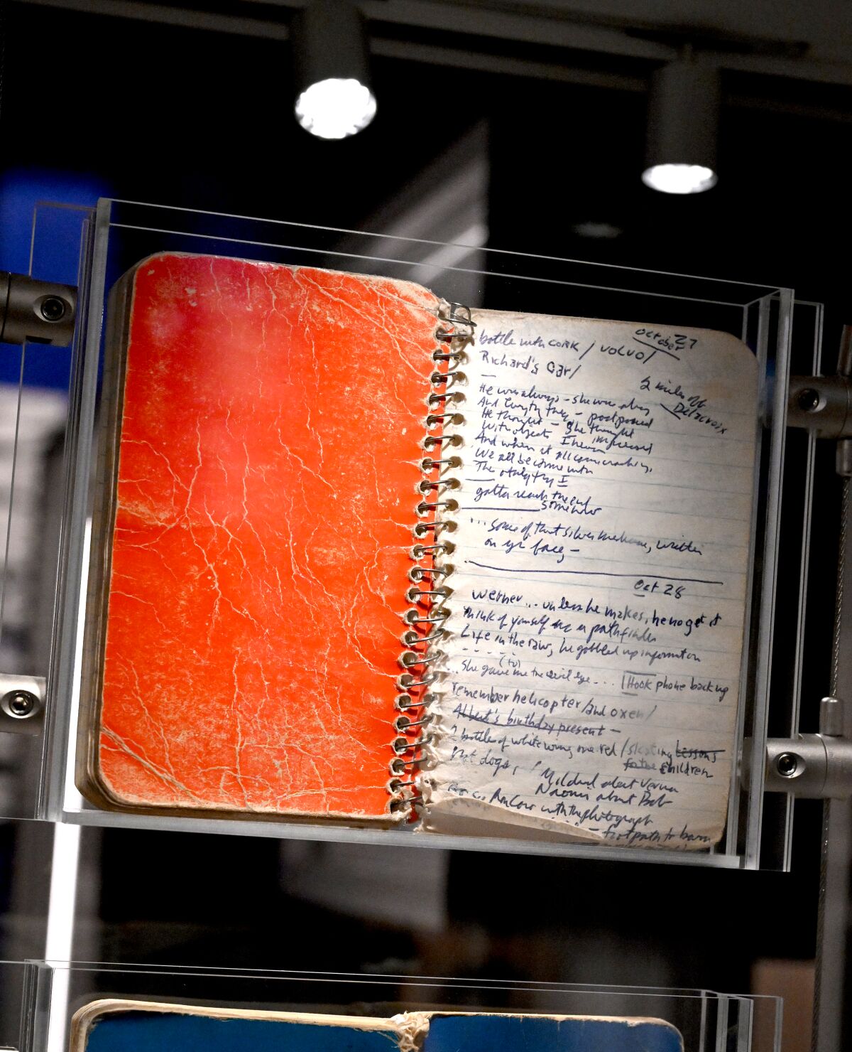 A notebook with handwritten lyrics in a museum display case