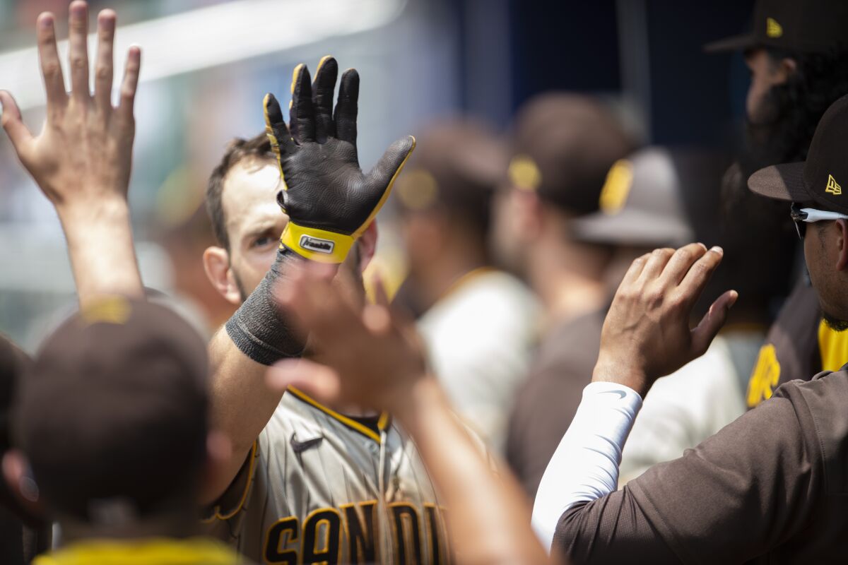 San Diego Padres' Wil Myers high-fives teammates after scoring during the seventh inning of a baseball game against Atlanta Braves, Sunday, May 15, 2022, in Atlanta. (AP Photo/Hakim Wright Sr)