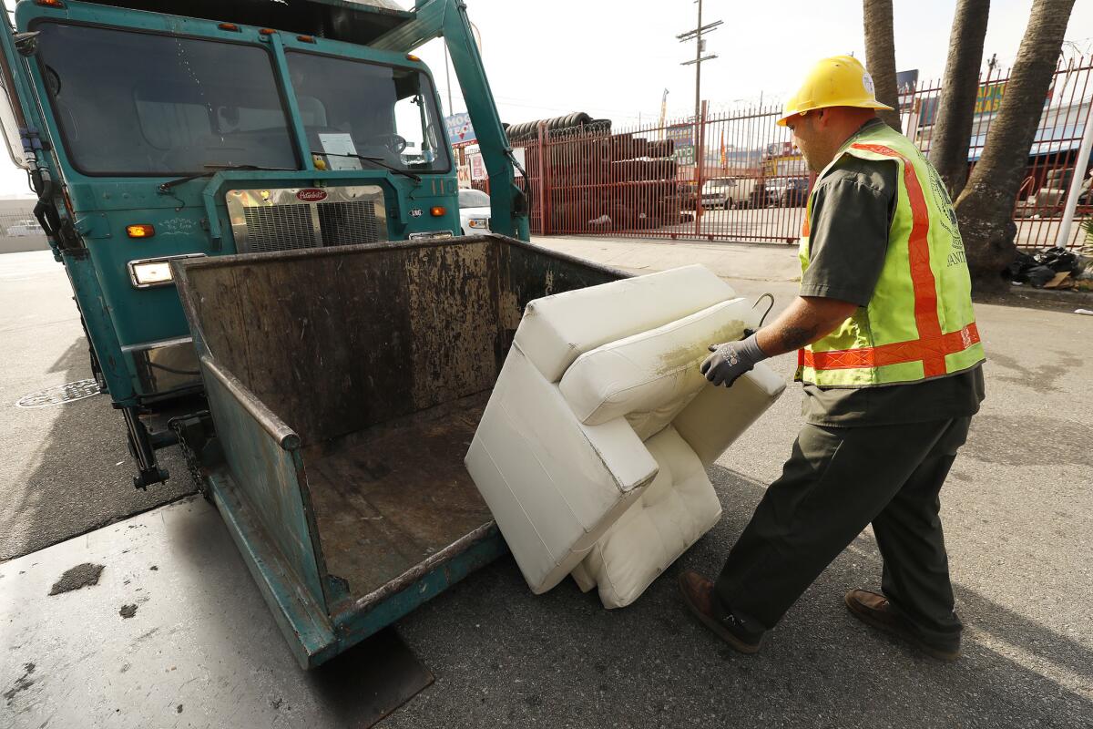 City of Los Angeles Bureau of Sanitation refuse collection truck operator Jake Nademlynsky, removes a sofa at 41st Place and Alameda Street.
