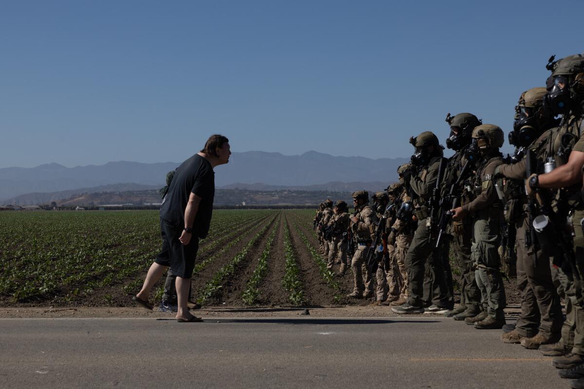 A protester confronts federal agents during an immigration raid at Glass House Farms cannabis operation.