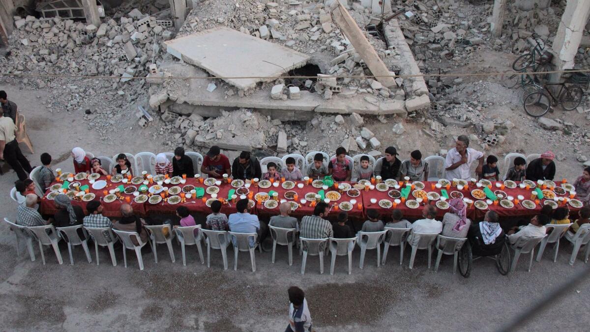 Syrian residents of the rebel-held town of Douma, on the outskirts of the capital Damascus, break their fast with the "iftar" meal on a heavily damaged street during the Muslim holy month of Ramadan.