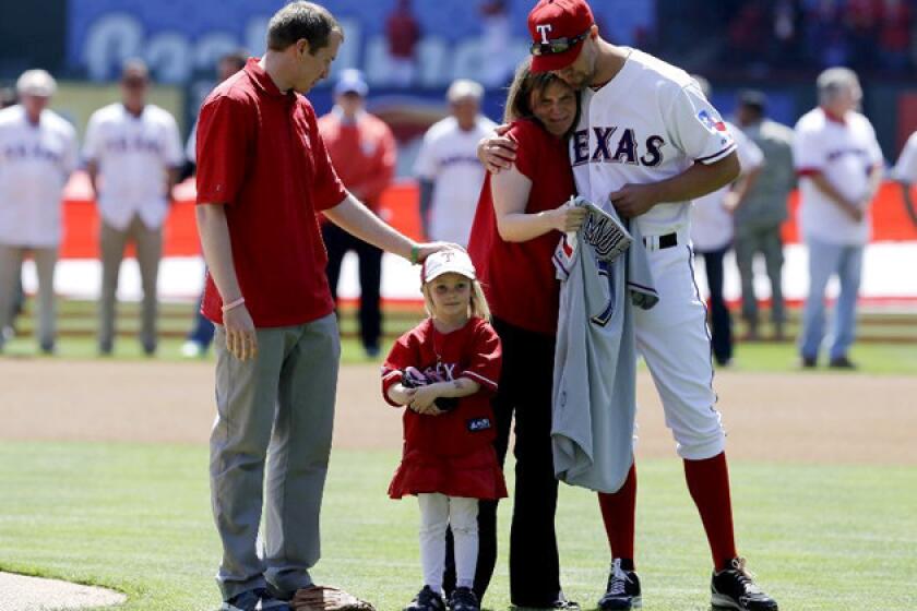 From left, Robbie Parker, daughter Samantha, wife Alissa and Texas Rangers' David Murphy gather on the field before Robbie threw out the ceremonial first pitch.