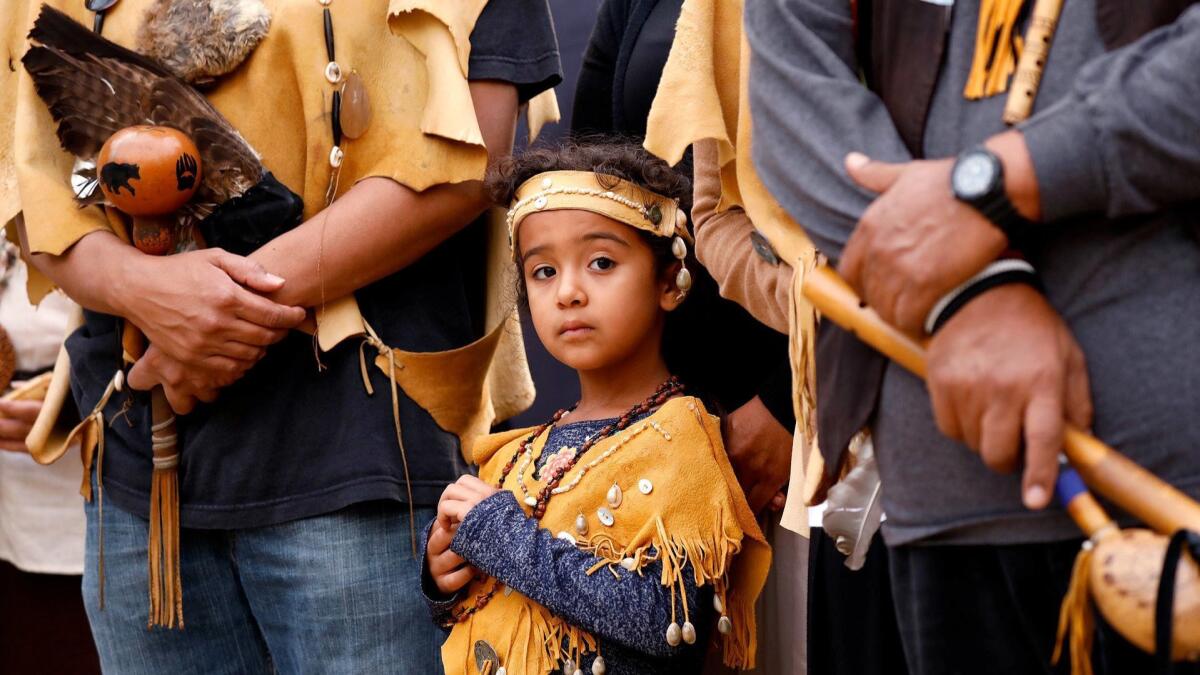 Ellie Morales Recalde, 5, with her mom, Mona Morales Recalde, attend the sunrise ceremony at North Main and 1st streets in downtown Los Angeles for the first celebration of Indigenous Peoples Day.