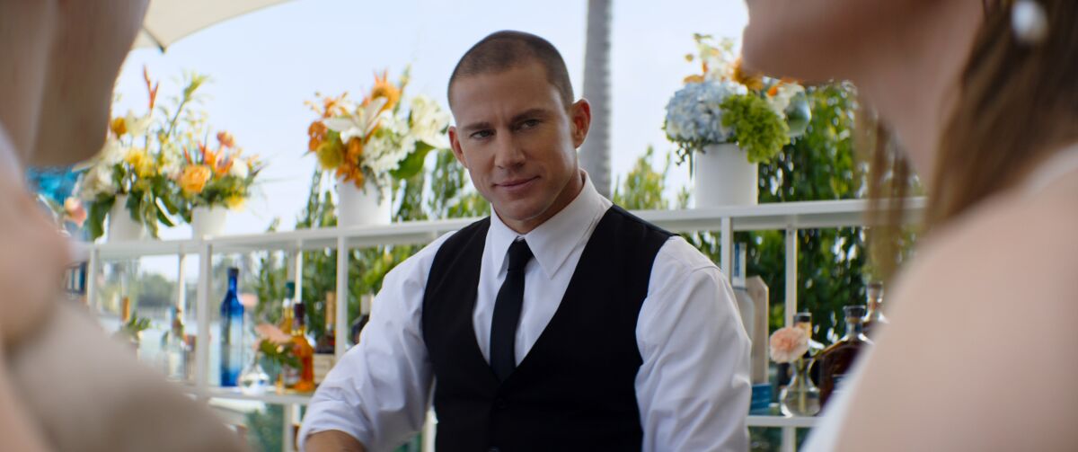 A man in formal attire bartends at an outdoor event.